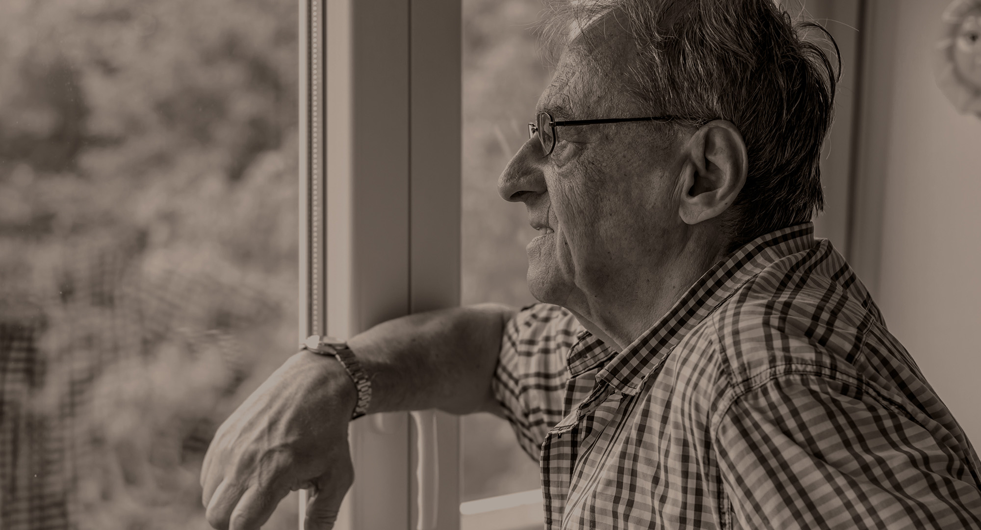 Older man looking pensively out of a window